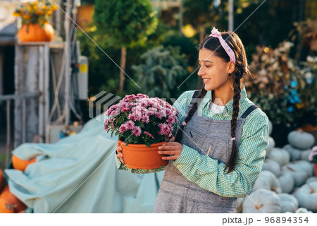 Woman holding decorative flower in flower pot on the market. 96894354