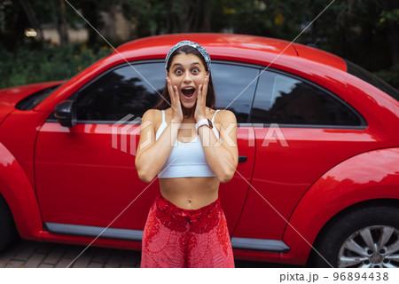 Portrait of pretty Caucasian woman standing against new red car Portrait of pretty Caucasian woman standing against new red car 96894438