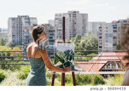 Young artist paints against the background of the city 96894439