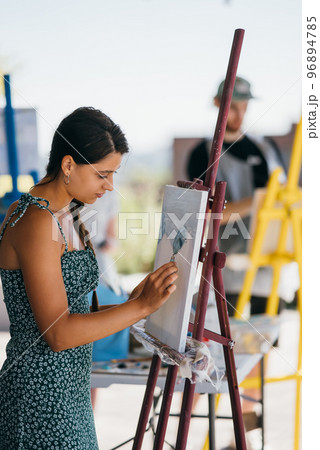 Young woman artist paints with a spatula on the canvas 96894785