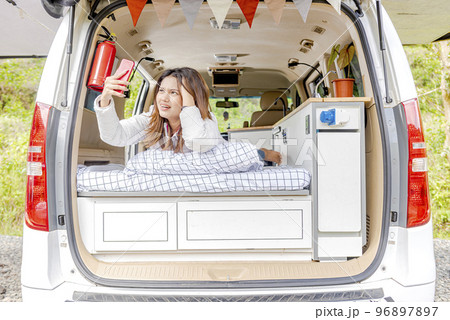 Asian woman searching the signal for her mobile phone inside the campervan 96897897