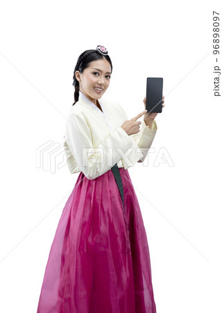 Asian woman wearing a traditional Korean national costume, Hanbok, standing while showing empty screen on mobile phone 96898097