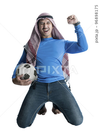 Asian man with keffiyeh holding the ball while celebrating victory with an excited expression Asian man with keffiyeh holding the ball while celebrating victory with an excited expression 96898175