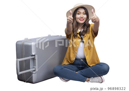 Asian woman with a hat and suitcase sitting showing thumb up Asian woman with a hat and suitcase sitting showing thumb up 96898322