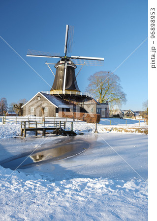 old historical wooden windmill in the snow in...の写真素材