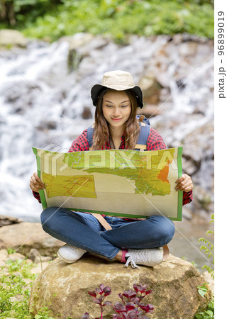 Asian woman in a hat and backpack holding maps 96899019