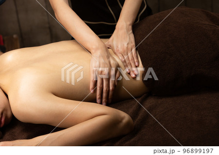 女性は背中のオイルマッサージを受けている。. 女性は背中のオイルマッサージを受けている。. 96899197