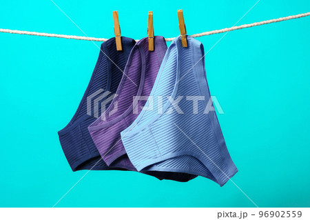 Female panties hanging on rope against blue studio background Female panties hanging on rope against blue studio background 96902559