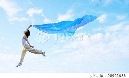 布を羽ばたかせ軽やかに空を飛ぶ女性 96905088