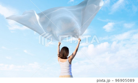 空に向けて布を羽ばたかせる女性 96905089