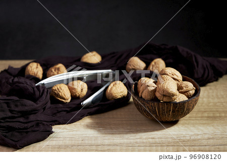 Close-up of tasty nuts in a bowl with a metal nutcracker on wooden table Close-up of tasty nuts in a bowl with a metal nutcracker on wooden table 96908120