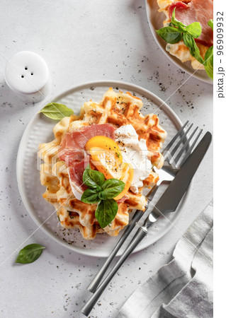 Cheese or potato savory waffles served with with tomatoes, cream cheese, ham and bazil leaves with cutlery. Delisious savory breakfast. Top view, flat lay 96909932