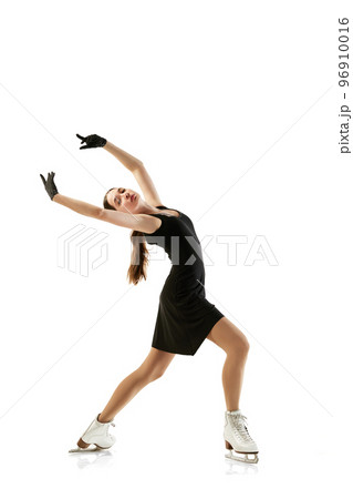 Portrait of flexible young girl, female figure skater in black stage costume skating isolated over white background. Junior athlete in motion. Sport, beauty, winter sports 96910016
