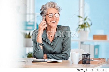 Phone call, communication and laughing with a senior woman sitting in her office, working alone and networking. Contact, mobile and business with a mature female employee joking while speaking 96915048
