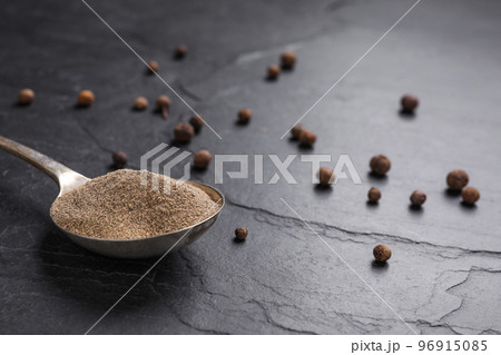 Ground black pepper and corns on black table, closeup Ground black pepper and corns on black table, closeup 96915085