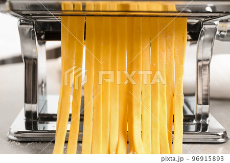 Pasta maker machine with dough on grey table, closeup Pasta maker machine with dough on grey table, closeup 96915893