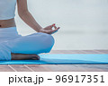 Woman in white yoga suit sitting meditating in the morning at lake. 96917351