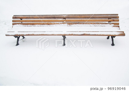 Wooden bench covered with snow. A bench in the park after a snowfall. Wooden bench covered with snow. A bench in the park after a snowfall. 96919046
