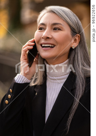 Long-haired mid aged woman with a smartphone looking anticipated 96922656