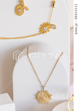Gold star shaped and other necklaces on white jewelry display stands. Girl accessories. 96924212