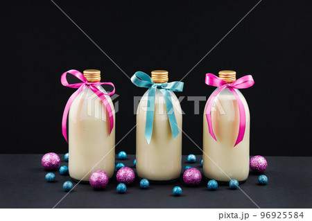 Homemade eggnog in bottles with pink and blue balls on dark background 96925584