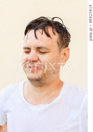 Young 32 years old european white male with closed eyes in water splash on yellow background. Man portrait, stress shock concept, mental health, rain, emotions, face expression, water drops. 96925614