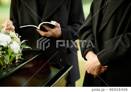 Outdoor funeral ceremony with priest reading prayer Outdoor funeral ceremony with priest reading prayer 96926406