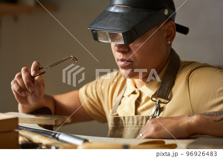 Close up of female jeweler wearing magnifying goggles Close up of female jeweler wearing magnifying goggles 96926483