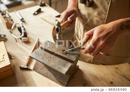 Jeweler creating handmade ring using anvil Jeweler creating handmade ring using anvil 96926490