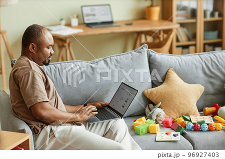 Single father working from home and using laptop 96927403