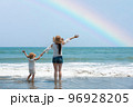 虹の出たビーチで両手を広げる親子 96928205