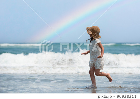 虹の出たビーチで遊ぶ少女 96928211