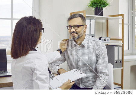 Female doctor therapist in white coat talking to male patient 96928686