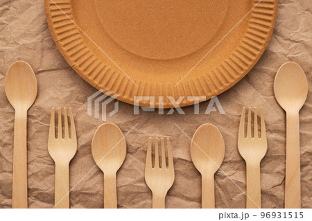 Wooden forks and spoons and paper plate on crumpled paper Wooden forks and spoons and paper plate on crumpled paper 96931515