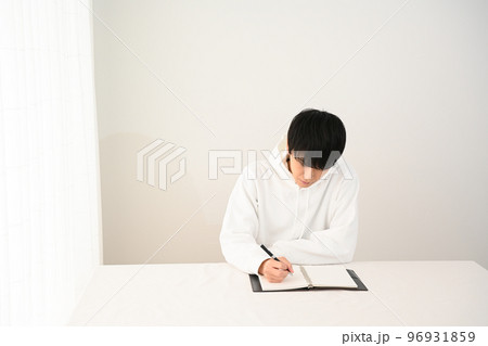 机でシステム手帳にペンで記入する若い男性 机でシステム手帳にペンで記入する若い男性 96931859