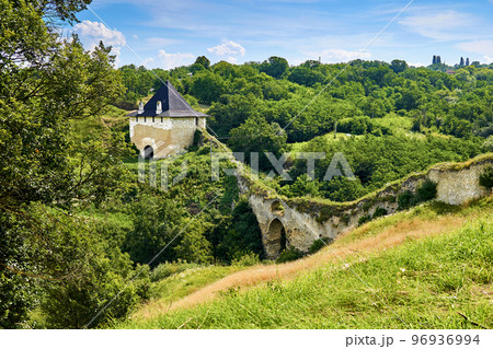 An ancient fortress wall with a watchtower on the hills overgrown with greenery 96936994