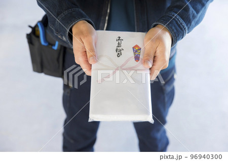 作業現場で挨拶用タオルを渡して挨拶をする作業員男性手元 96940300