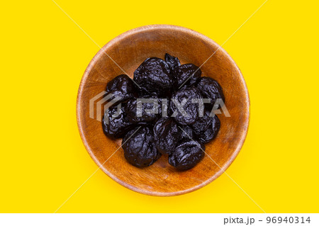 Dried prunes on yellow background Dried prunes on yellow background 96940314