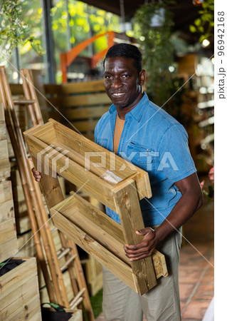Attentive american african man choosing wooden pallets in shop Attentive american african man choosing wooden pallets in shop 96942168