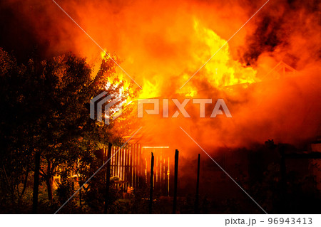 Wooden house or barn burning on fire at night. Wooden house or barn burning on fire at night. 96943413