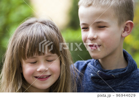 Two cute fair-haired children siblings, young boy brother and sister girl outdoors on bright sunny green bokeh background. Family relation, friendship and love concept. Two cute fair-haired children siblings, young boy brother and sister girl outdoors on bright sunny green bokeh background. Family relation, friendship and love concept. 96944029