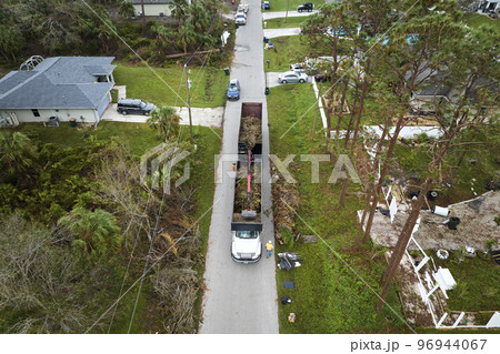 Top view of Hurricane Ian special aftermath recovery dump truck picking up tree branches debris from Florida rural streets. Dealing with consequences of natural disaster 96944067