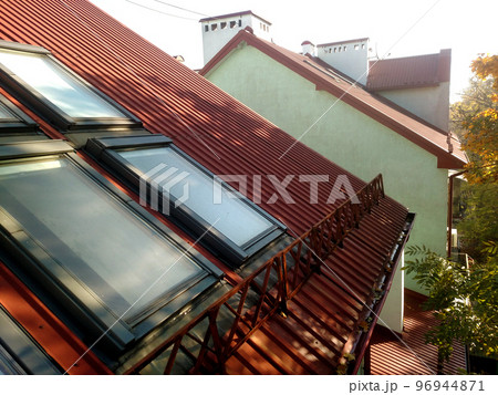 Red tiled house roof with attic windows. Roofing construction, window installation, modern architecture concept. 96944871