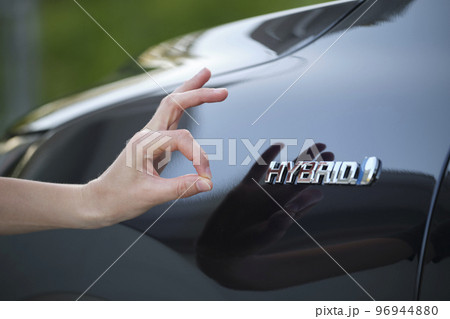 Purchaser hand showing thumb up sign at hybrid car new effective vehicle Purchaser hand showing thumb up sign at hybrid car new effective vehicle 96944880