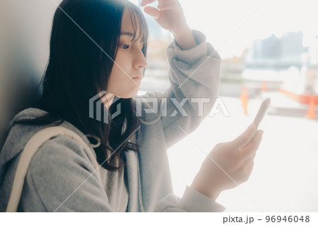 女子高生が街中でスマホを持った写真 96946048