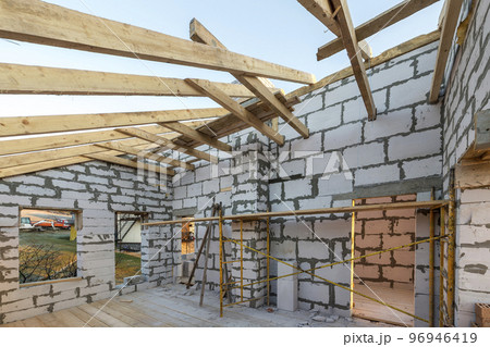 House interior under construction and renovation. Energy saving walls of hollow foam insulation blocks and bricks, ceiling beams and roof frame. 96946419