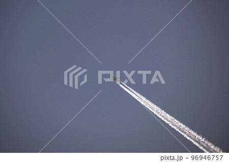 Distant passenger jet plane flying on high altitude on clear blue sky leaving white smoke trace of contrail behind. Air transportation concept Distant passenger jet plane flying on high altitude on clear blue sky leaving white smoke trace of contrail behind. Air transportation concept 96946757
