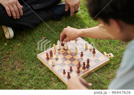 Man playing chess with his senior father on lawn in city park 96947626