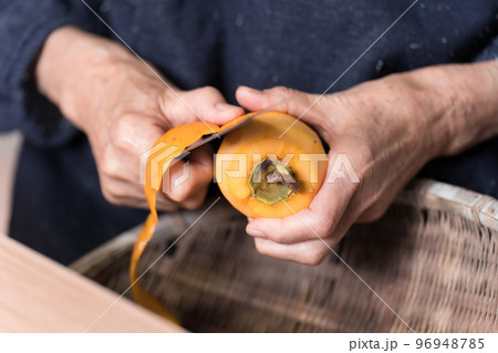 包丁で渋柿の皮を剥いているシニア女性 包丁で渋柿の皮を剥いているシニア女性 96948785