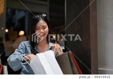 Attractive Asian woman opening her shopping bags, checking her purchase stuff 96954910